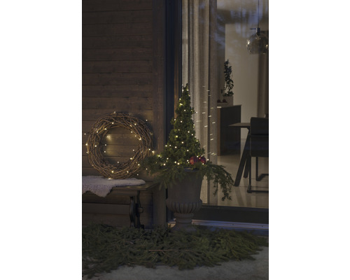 Véranda décorée avec couronne illuminée et arbre dans un vase