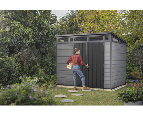Scène de jardin avec cabanon et femme portant une caisse
