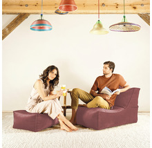 Aménagement de salon avec un couple assis sur des poufs avec dossier, une table d''appoint et des lampes colorées