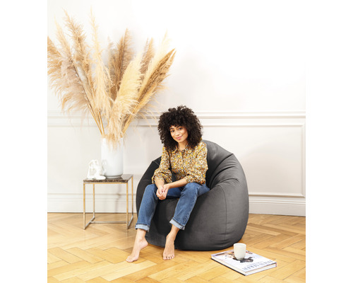 Frau sitzt in einem grauen Sitzsack in einem hellen Raum.