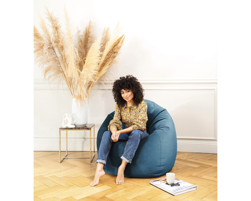 Frau sitzt in einem blauen Sitzsack in einem hellen Wohnzimmer