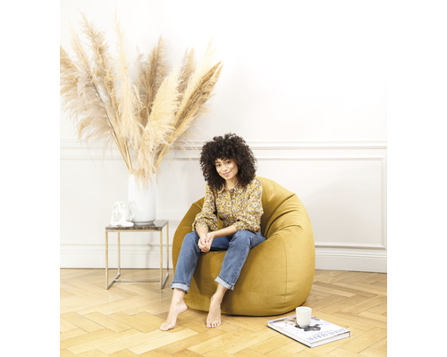 Frau sitzt auf einem gelben Sitzsack im Wohnzimmer
