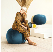 Femme assise sur un pouf bleu dans un salon.