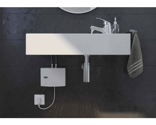 Salle de bains moderne avec vasque à poser, robinet, serviette et chauffe-eau instantané électronique AEG