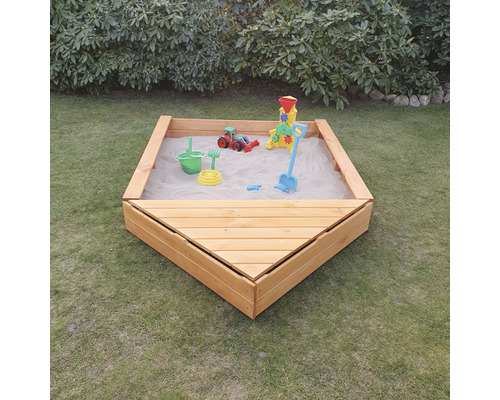 Bac à sable en bois avec sable et jouets dans le jardin