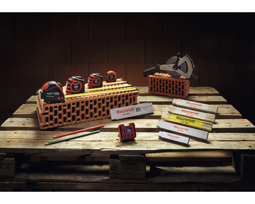 Assortiment d''outils de maçonnerie sur palette en bois avec mètres à ruban, odomètre, mètres pliants, crayons et horloge numérique