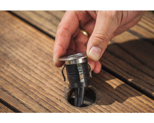 Spot encastrable en cours d''installation dans une terrasse en bois