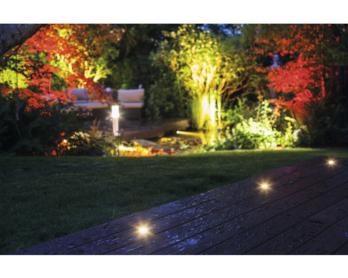 Jardin illuminé avec spots encastrés dans le sol sur terrasse en bois