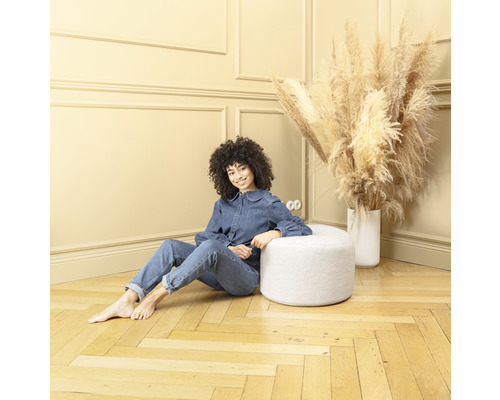 Femme assise à côté d''un tabouret blanc dans une pièce avec plancher en bois