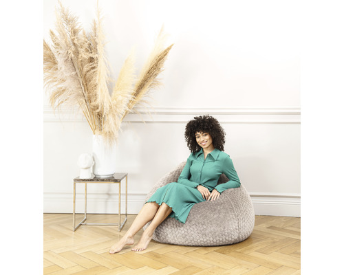 Femme assise dans un pouf gris dans une pièce lumineuse