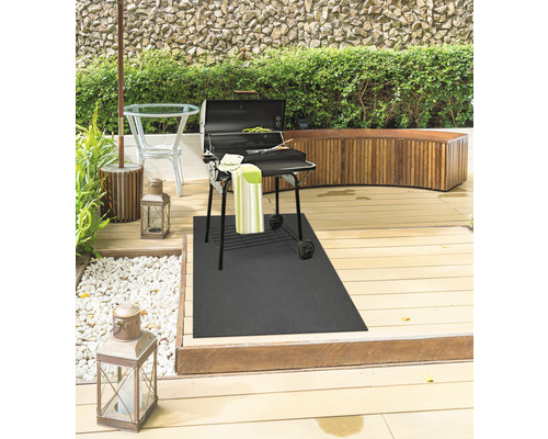 Espace barbecue avec grill, tapis de grill, table et banc sur une terrasse en bois