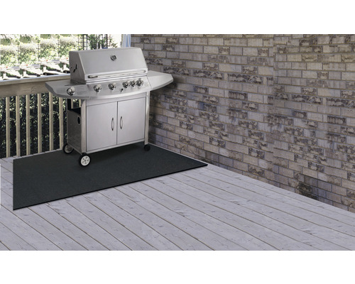 Scène avec un barbecue à gaz sur un tapis de protection sur une terrasse en bois.
