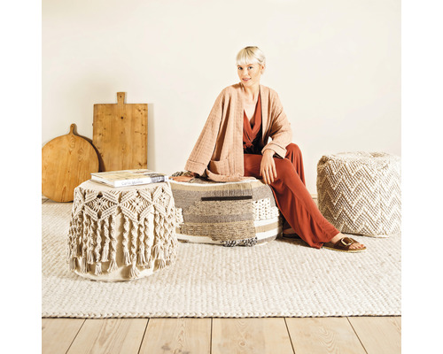 Scène d''intérieur avec une femme assise sur un pouf, d''autres poufs et des assiettes en bois en arrière-plan