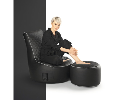 Frau sitzt in einem schwarzen Sessel mit Fußhocker