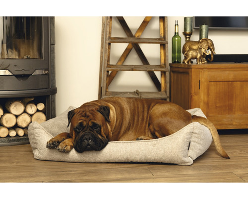 Ein Hund ruht auf einem Hundebett neben einem Kamin mit Holz.