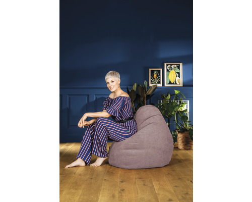 Frau sitzt auf einem grauen Sitzsack in einem Wohnzimmer.