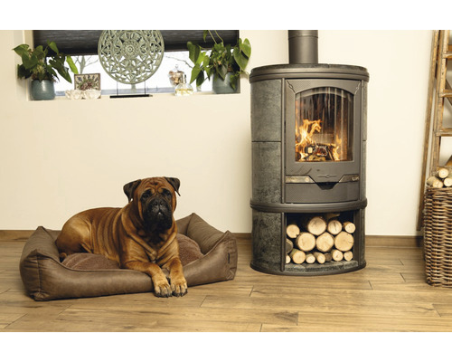 Bullmastiff allongé dans un panier pour chien à côté d''un poêle à bois avec compartiment à bois