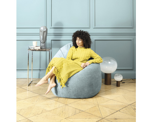 Femme assise dans un pouf bleu dans un salon