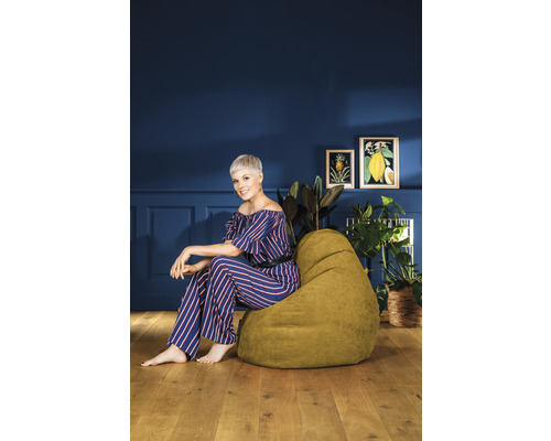 Frau sitzt auf einem grünen Sitzsack in einem Zimmer mit Dekoration