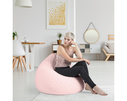 Frau sitzt auf einem rosafarbenen Sitzsack in einem hellen Wohnraum.