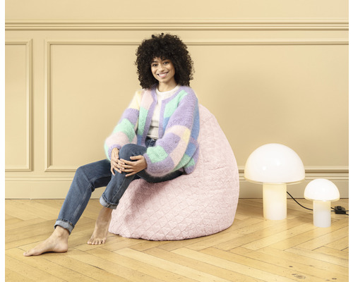 Frau sitzt auf einem rosa Sitzsack neben zwei Lampen in Pilzform