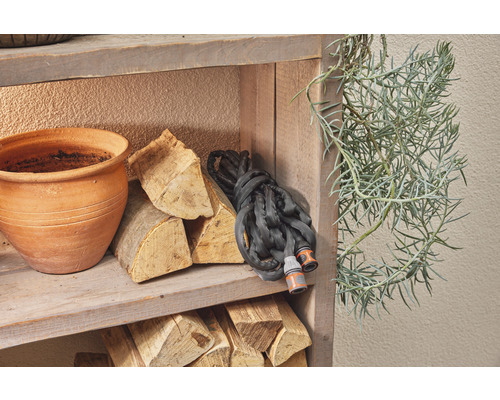 Étagère avec tuyau d''arrosage, briquettes de bois, pot de fleurs et plante