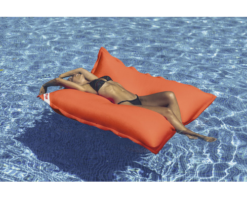 Femme se détend sur un îlot de piscine orange dans la piscine