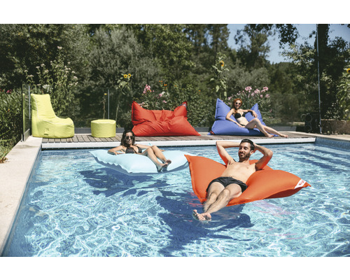 Scène avec piscine et personnes détendues sur des coussins flottants et des poufs au bord de la piscine