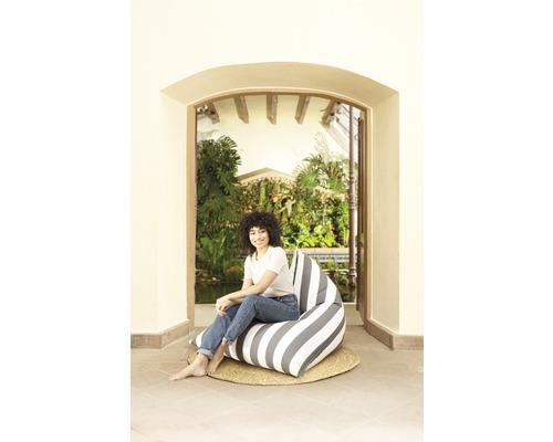 Femme assise sur un pouf rayé sur un tapis tressé