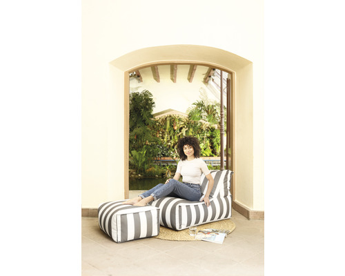 Femme assise sur un pouf avec repose-pieds rayé