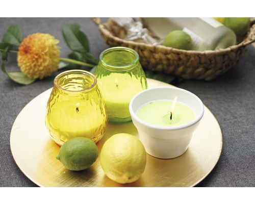 Arrangement décoratif avec bougies parfumées, citron et citron vert sur une assiette dorée.