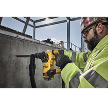 Un ouvrier perce un trou dans un mur en béton avec un marteau perforateur DeWalt.