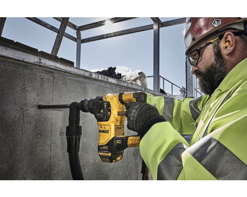 Un ouvrier perce un trou dans un mur en béton avec un marteau perforateur DeWalt.