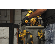 Un homme utilise un marteau perforateur DeWalt pour percer un mur de briques.