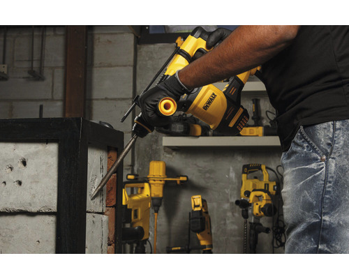 Un homme utilise un marteau perforateur DeWalt pour percer un mur de briques.