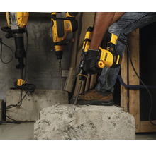 Un artisan utilise un marteau-piqueur DeWalt pour travailler le béton. D'autres marteaux perforateurs sont prêts en arrière-plan.