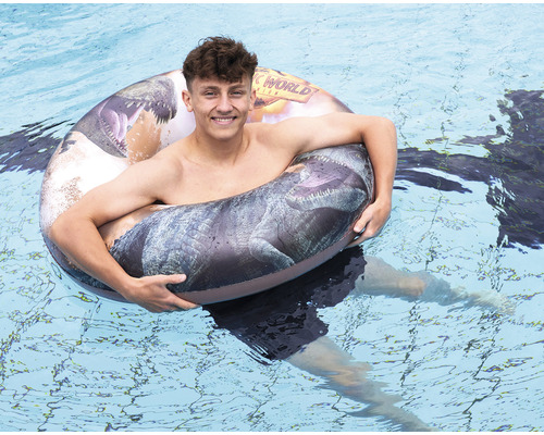Eine Person schwimmt mit einem Jurassic World Schwimmreifen im Schwimmbad.