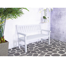 Banc de jardin blanc sur sol en pierre devant un mur