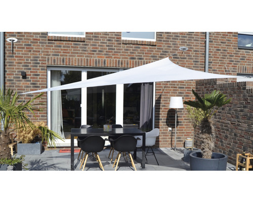 Terrasse avec voile d''ombrage, table et chaises devant une maison en brique