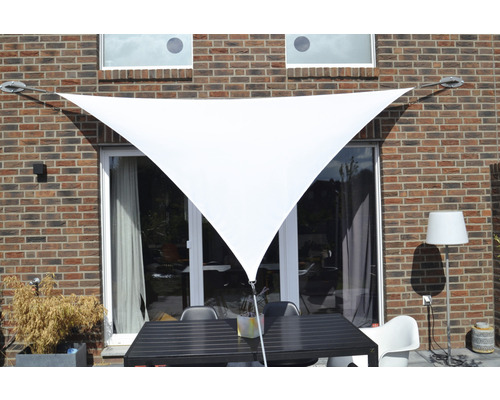 Dreieckiges Sonnensegel vor einer Hauswand mit Terrassenmöbeln