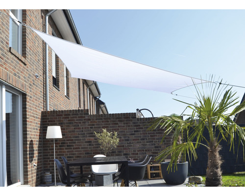 Terrasse mit Sonnensegel, Tisch und Stühlen vor einer Backsteinmauer