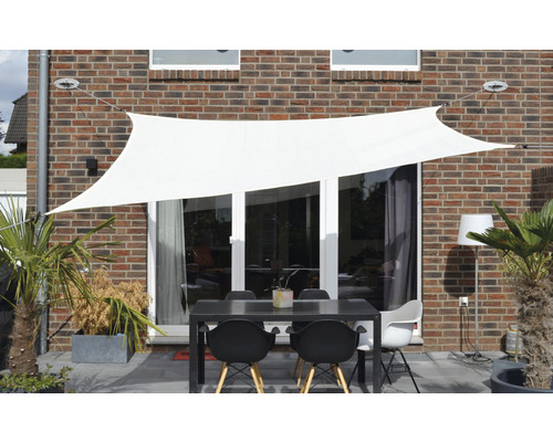 Terrasse avec voile d''ombrage, table et chaises devant un mur de maison