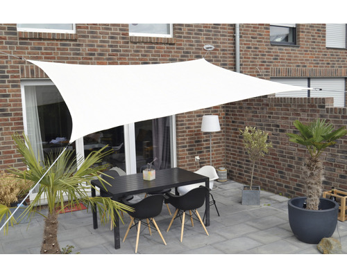 Terrasse avec voile d''ombrage, table et chaises devant un bâtiment en briques