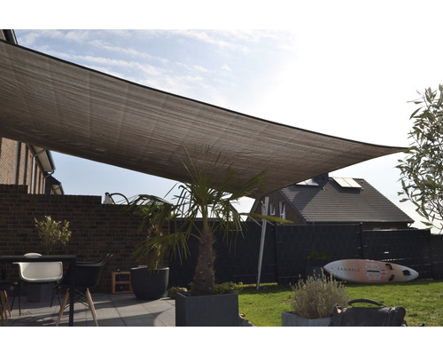 Sonnensegel über einer Terrasse mit Gartenmöbeln und Pflanzen.