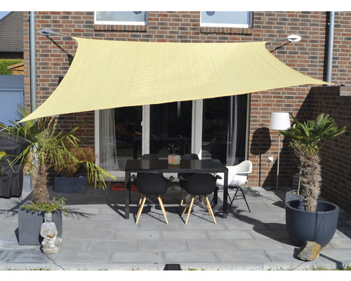Terrasse avec voile d''ombrage, table et chaises devant un bâtiment en briques