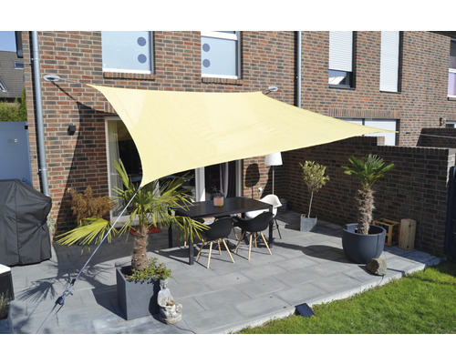 Terrasse avec voile d''ombrage, table et chaises devant une maison en briques
