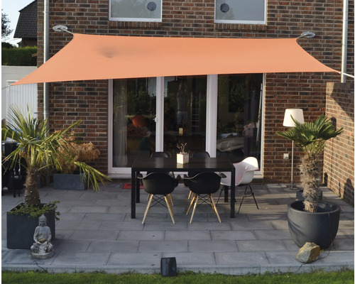 Terrasse avec voile d''ombrage et mobilier de jardin devant une maison