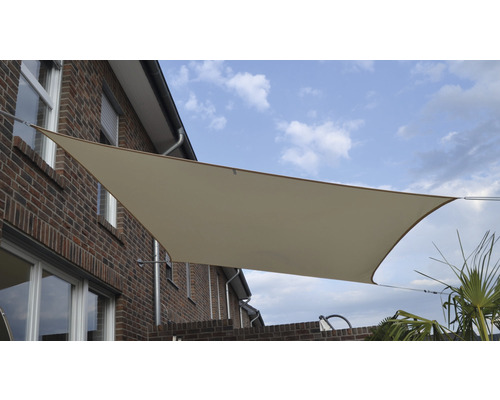 Beiges Sonnensegel an einem Backsteingebäude mit blauem Himmel