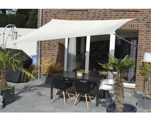 Terrasse avec voile d''ombrage, table de jardin et chaises devant un mur de maison