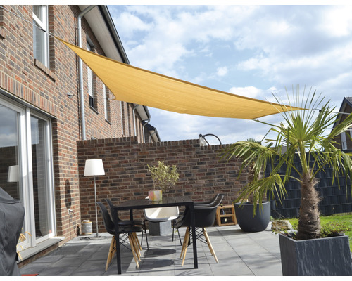 Terrasse avec voile d''ombrage, table et chaises devant une maison